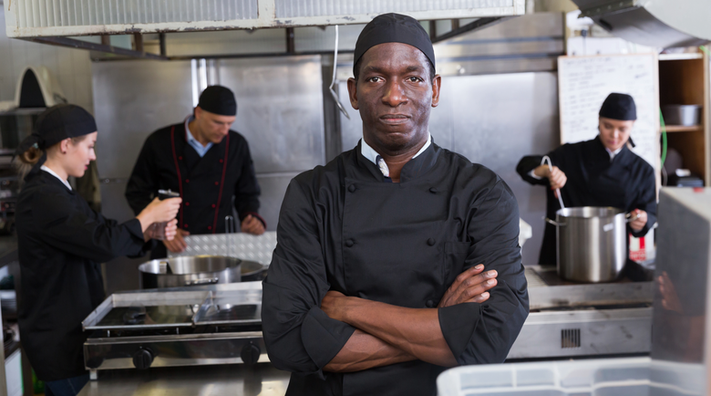 Chef wearing black chef jacket in kitchen - chef jackets - chef uniform