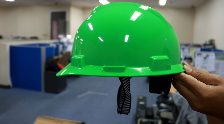 Green hard hat with chin strap being held up - hard hat chin strap - hard hat