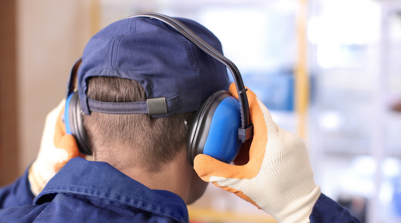 Man putting on ear muffs - ear protection - safety ear protection